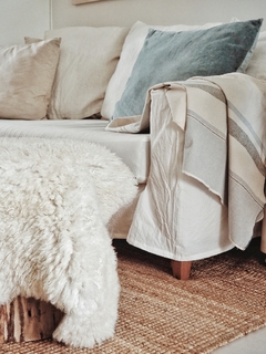 Corderito de cuero de oveja color natural sobre un sofá con cojines claros.