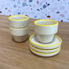 Xícaras de Café com Pires Elo Abacaxi empilhadas. Na cor Off White, com a bordas Amarela, formato Moderno. Perfeitas para cafés afetivos e momentos especiais.