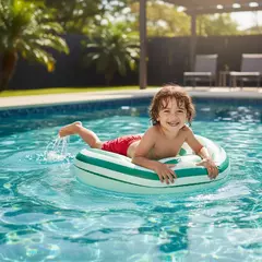 Niño sonriente jugando en una pileta con una dona inflable rayada verde y blanca