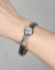 Bracelete em metal prata com pedra Rivoli cristal, adornando um pulso humano.