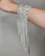 Bracelete prateado em strass com franjas, adornando um pulso feminino.