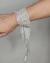 Bracelete prateado em strass com franjas, adornando um pulso feminino.