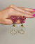 Brinco dourado com strass em forma de coração rosa e símbolo de paz.