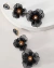 Brinco Festa Flores Preto com Pedrarias, apresentando flores pretas e detalhes em pedrarias.