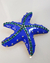 Broche dourado em forma de estrela do mar, esmaltado em azul e decorado com strass verde.