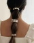 Mulher com cabelo preso em um coque baixo, adornado com elásticos de cabelo dourados.