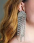 Brinco maxi de strass em cascata, com design elegante e brilhante, usado por uma mulher com cabelo castanho claro.