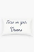 Almofada retangular branca com bordado azul marinho escrito "Focus on your Dreams"