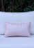 Almofada retangular em tricot nas cores rosé e offwhite, posicionada sobre um fundo claro.