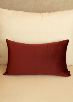Almofada retangular de veludo na cor marsala, posicionada sobre um sofá claro.