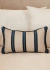 Almofada retangular com listras em azul marinho e cru, ideal para decoração de quartos.