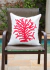 Almofada quadrada impermeável com estampa de coral vermelho sobre um fundo branco, posicionada em uma cadeira ao lado de uma piscina.