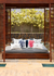 Almofada impermeável coral azul marinho quadrada em um ambiente externo relaxante, rodeada por outras almofadas decorativas com temas náuticos.