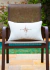 Almofada retangular bordada com tema de bússola, posicionada em uma cadeira ao lado de uma piscina, ideal para ambientes externos.