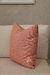 Almofada em linho coral, com textura suave, sobre um sofá claro.