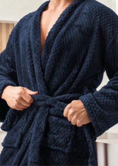 Homem vestindo roupão azul clássico tamanho G, com textura macia e amarrando o cinto na cintura