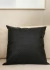 Almofada de couro preto com padrão texturizado, ideal para decoração de ambientes elegantes.