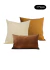 Conjunto de três almofadas nas cores caramelo, bege e marrom, ideal para decoração de ambientes.