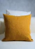 Almofada caramelo texturizada em destaque, com fundo claro, em ambiente decorativo.