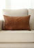 Almofada de couro caramelo sobre um sofá claro, parte de um kit de 3 peças ideal para decoração de outono/inverno.