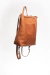 Mochila de cuero sin forrería. Puede convertirse en bolso para llevar al hombro intercambiando la posición de las correas.

Tiene un bolsillo interno y otro externo en la espalda con cierre metálico.