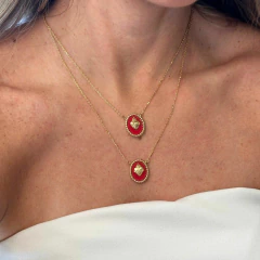 Colar escapulário com dois pingentes do Sagrado Coração em ouro, usados por mulher com blusa branca