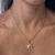Colar com pingente Sun Duo em formato de sol dourado com detalhes em zricônias cristais usado no pescoço de uma mulher