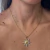 Colar com pingente Sun Duo em formato de sol dourado com detalhes em zricônias cristais usado no pescoço de uma mulher