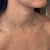 Colar choker delicado em ouro com pequenas pérolas penduradas no pescoço de mulher