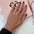 Pulseira de mão ponto de luz em ouro com pequenos cristais, usada em uma mão feminina com unhas pintadas de preto