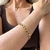Pulseira Elos Impulse em ouro no pulso de mulher vestindo blusa marrom