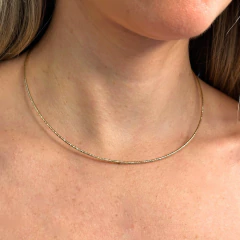 Choker aro diamantado em ouro, destacando o pescoço de uma mulher.