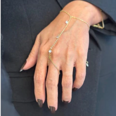 Pulseira de mão ponto de luz em ouro com pingentes de pedras brilhantes, usada em mão feminina com esmalte escuro