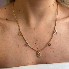 Colar dourado Nossa Senhora das Graças com pingentes religiosos usando no pescoço de uma pessoa