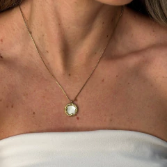 Colar delicado com pingente redondo de madrepérola em moldura dourada usado no pescoço de mulher