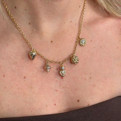 Colar Jardim Secreto em ouro com diversos pingentes, incluindo coração, flor e cogumelo, exibido em um pescoço feminino.