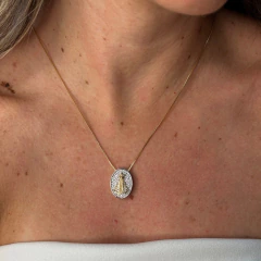 Colar com pingente oval de Nossa Senhora Aparecida em tons dourado e prateado usado no pescoço de mulher