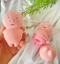 Vibrador masturbador en forma de cerdito, color rosa, con detalles sonrientes y partes desmontables. Incluye cable de carga.