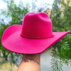 Chapéu Sibu Jeito de Cowboy na cor rosa pink, com aba larga, segurado por uma mão.
