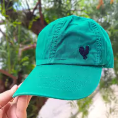 Boné verde da marca Made In Mato com bordado de um galo na lateral.