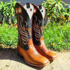 Bota Masculina Tex Team Carrapeta Laranja em destaque, com detalhes em couro preto e laranja, em um fundo de grama verde.
