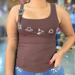 Regata feminina marrom Thankfield com fivela prata no ombro e estampas brancas frontais, usada com calça jeans azul.