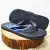 Chinelo masculino Acostamento azul com detalhe em preto e logo prateado, apoiado em um tronco de madeira.