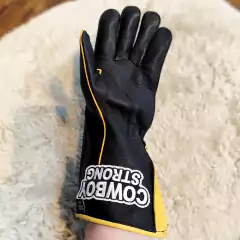 Luva para montaria em touros da marca Cowboy Strong, com design preto e detalhes em amarelo.