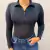 Body feminino preto com zíper na parte frontal, utilizado por uma mulher, combinado com jeans.