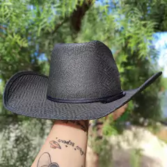 Chapéu Eldorado preto de lona cru infantil, com aba larga, segurado por uma mão em um ambiente natural.