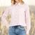 Camisa cropped feminina rosa com detalhes em botão e gola, combinada com jeans decorados.