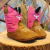 Bota infantil rosa e marrom da marca Tex Team, com detalhes em bordado, sobre uma superfície de madeira.