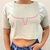 Cropped feminina bege com estampa de chifre rosa na frente.