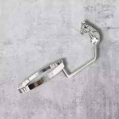 Suporte para chapéu em formato de cabeça de cavalo, com acabamento prateado, sobre fundo cinza.